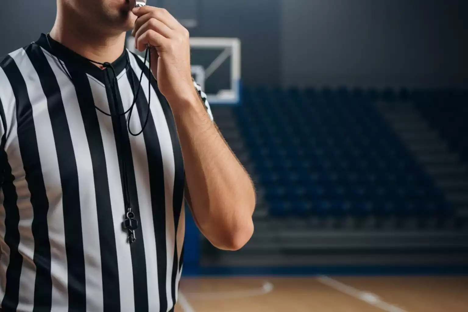Nahaufnahme eines NBA-Schiedsrichters in gestreiftem Hemd mit Pfeife auf dem Spielfeld als Symbol für Spielintegrität und Wett-Überwachung